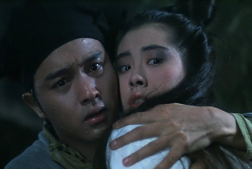 A scene from the 1987 Hong Kong film A Chinese Ghost Story showing a man and woman with their heads close together, looking worried.