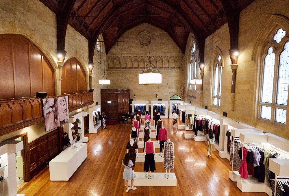 The interior of a designer store with vaulted ceilings and rows of mannequins.