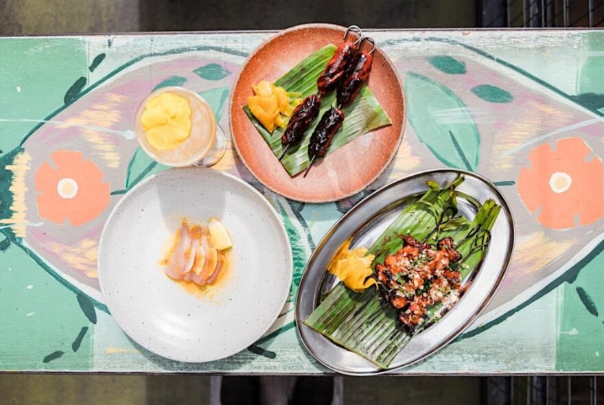 Three Filipino dishes presented on a table with a peachy-green floral print.