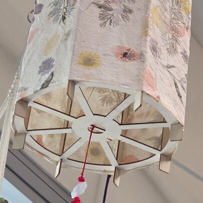 A decorated lampshade featuring homemade paper and pressed flowers. 