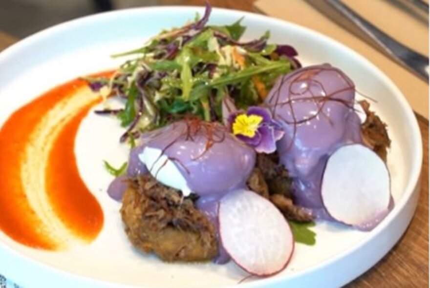 A plate of food with a side salad and a smear of sauce on the side.