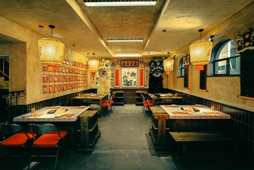 Interior of a restaurant showing tables and chairs set for service, hanging lights.