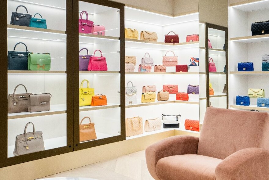 Store shelving units filled with multicoloured designer handbags.