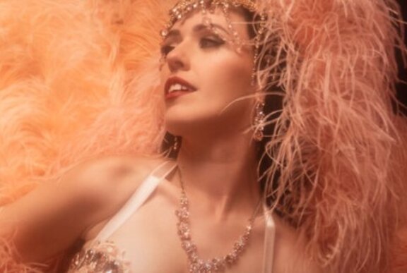 Burlesque dancer wearing pink feathers and jewels.
