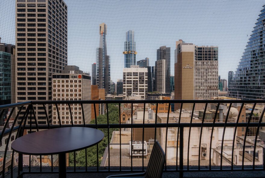 View of the Melbourne city skyline from a balcony with a small round table.