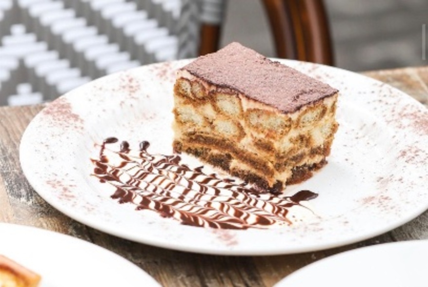 Slice of tiramisu dessert on a plate.