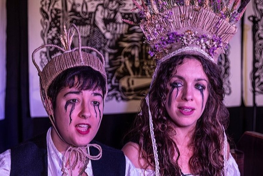 A couple wearing crowns and white makeup with black tears.