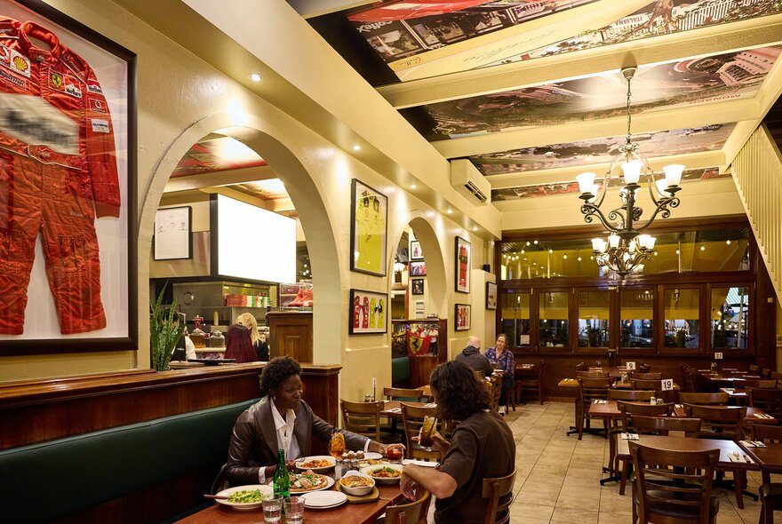 A couple dining in an Italian restaurant with Ferrari merch on the walls.