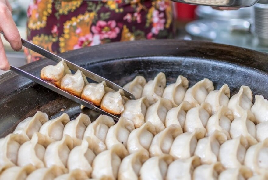 A huge pan of dumplings steaming in the open air.