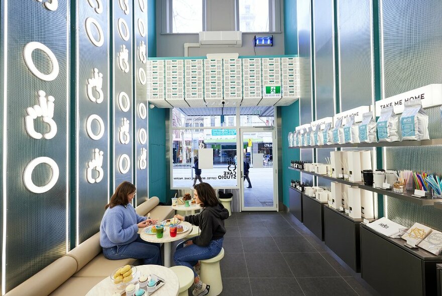 Two women dining in a futuristic silver cafe.