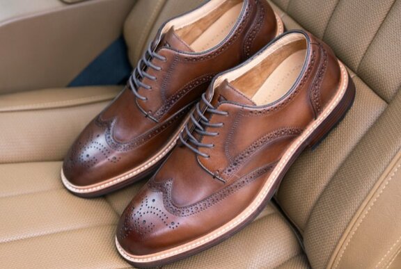 Pair of brown tooled leather shoes resting on a leather car seat.