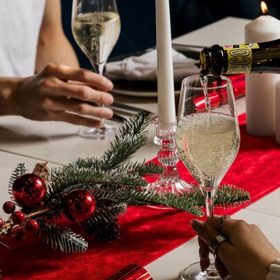 Christmas decorations on a table and champagne being poured into a glass.