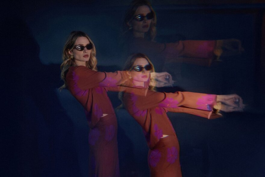 A fashion model wearing a tan coloured dress and sunglasses, her image duplicated to the right of her and also behind her, against a dark background.