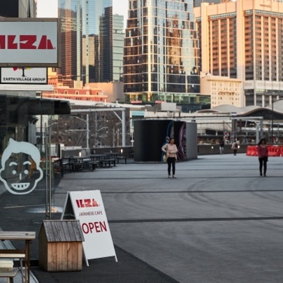 The signage outside Ilza restaurant near Marvel Stadium, with a view of city buildings in the background.