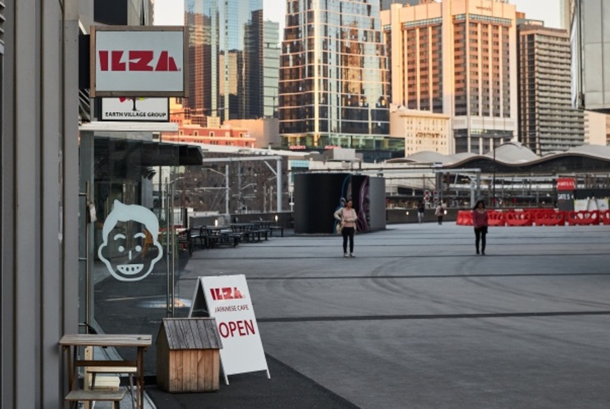 The signage outside Ilza restaurant near Marvel Stadium, with a view of city buildings in the background.