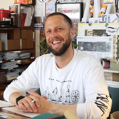 Australian comics journalist and illustrator Sam Wallman smiling in his studio.
