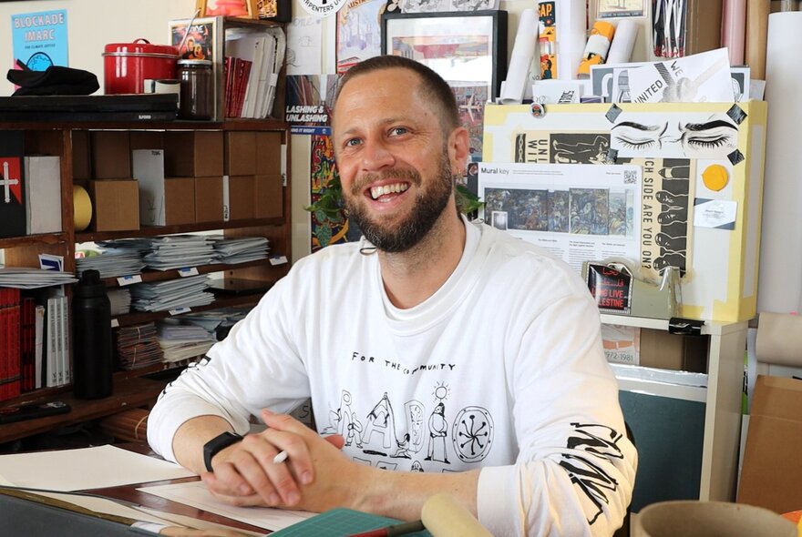 Australian comics journalist and illustrator Sam Wallman smiling in his studio.