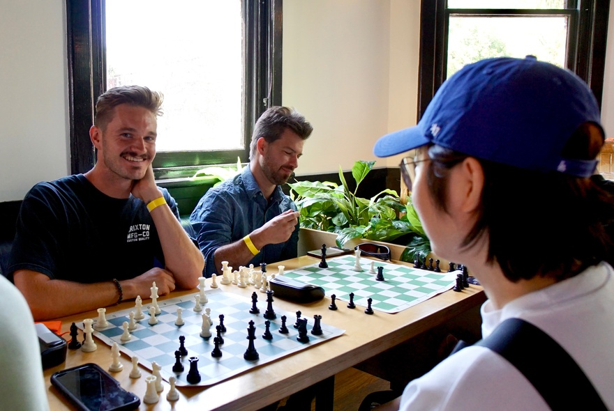A social chess gathering where people are playing chess matches in an indoor setting of a bar.