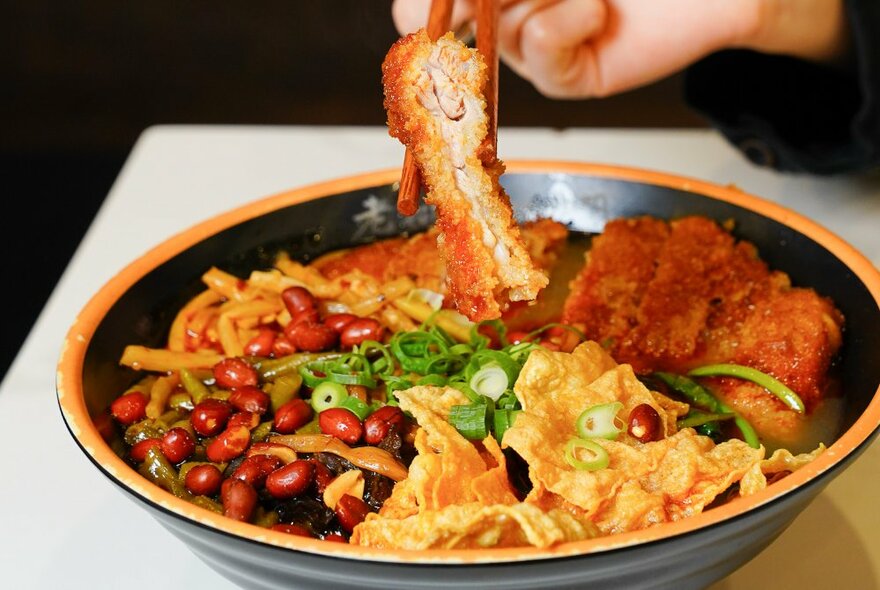 Bowl of noodles, crispy pork and vegetables.