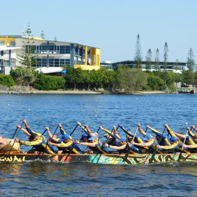 People rowing on a dragon boat on a river. 