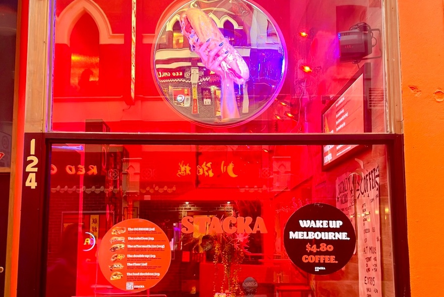 Exterior of Stacka shopfront, with large signs on the window and a view into a warm red coloured interior.