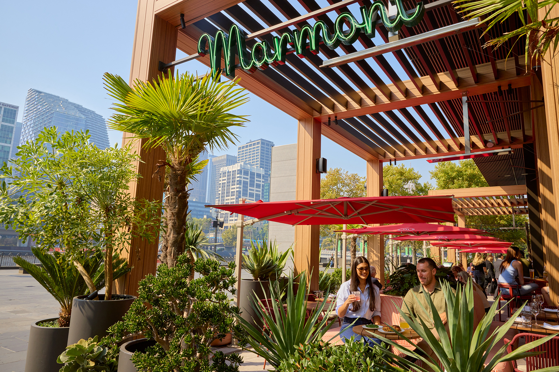 A couple sitting outside a restaurant surrounded by plants.