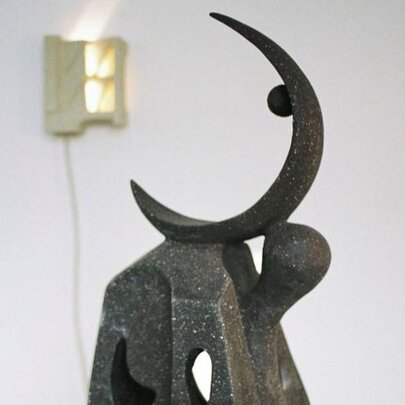 Metal sculpture of a slender half moon in an exhibition space.