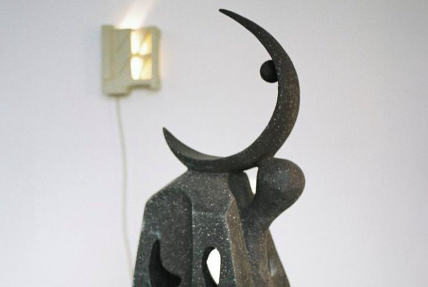 Metal sculpture of a slender half moon in an exhibition space.