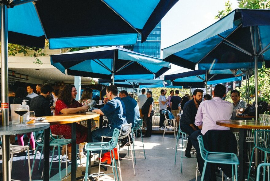 People seated outside under shade umbrellas.