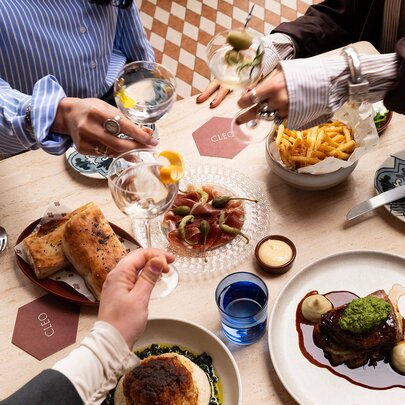 A restaurant table with share plates and three martinis.