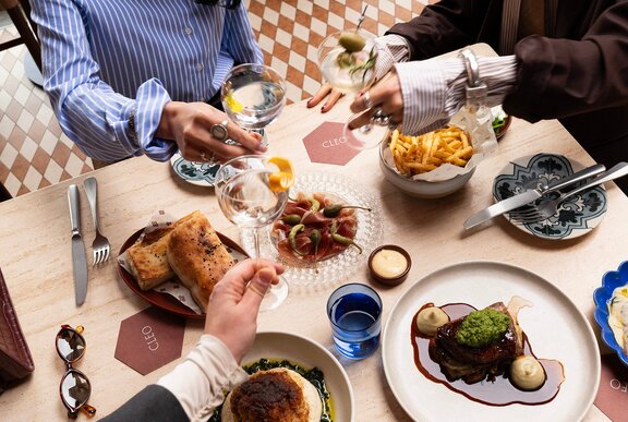 A restaurant table with share plates and three martinis.