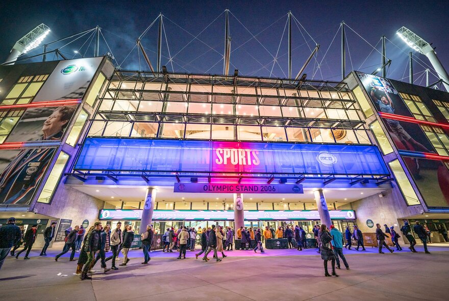 A crowd is gathered at the entrance of the MCG stadium for an AFL game