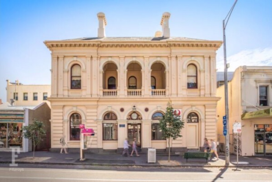 Large heritage building with arcaded first-floor and arched windows and doors on ground-floor level.
