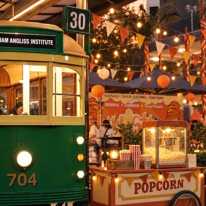 The William Angliss Institute Tram Café, and the courtyard decorated for a outdoor market with festive lanterns, bunting an a popcorn cart. 