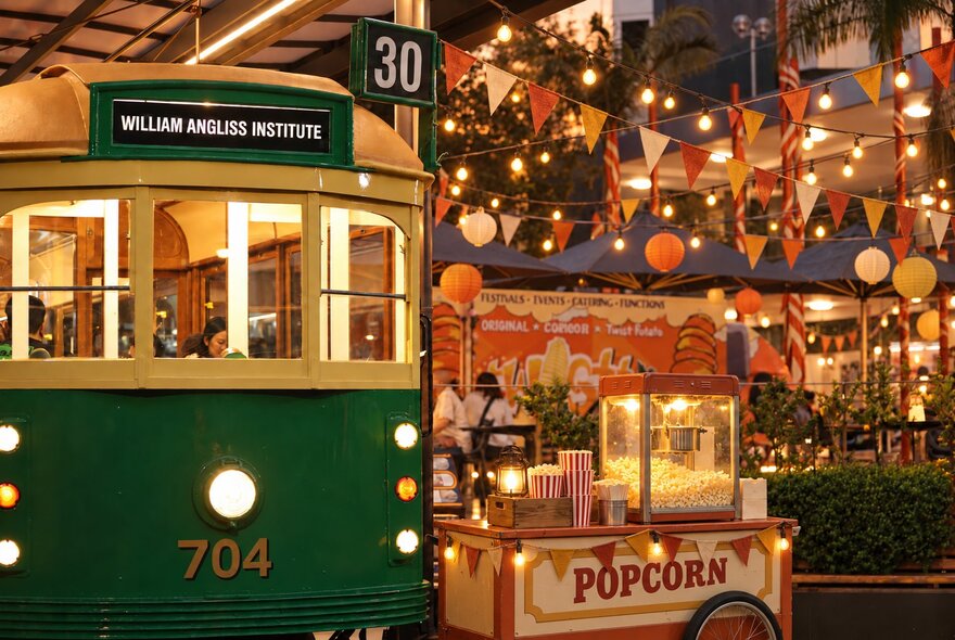 The William Angliss Institute Tram Café, and the courtyard decorated for a outdoor market with festive lanterns, bunting an a popcorn cart. 