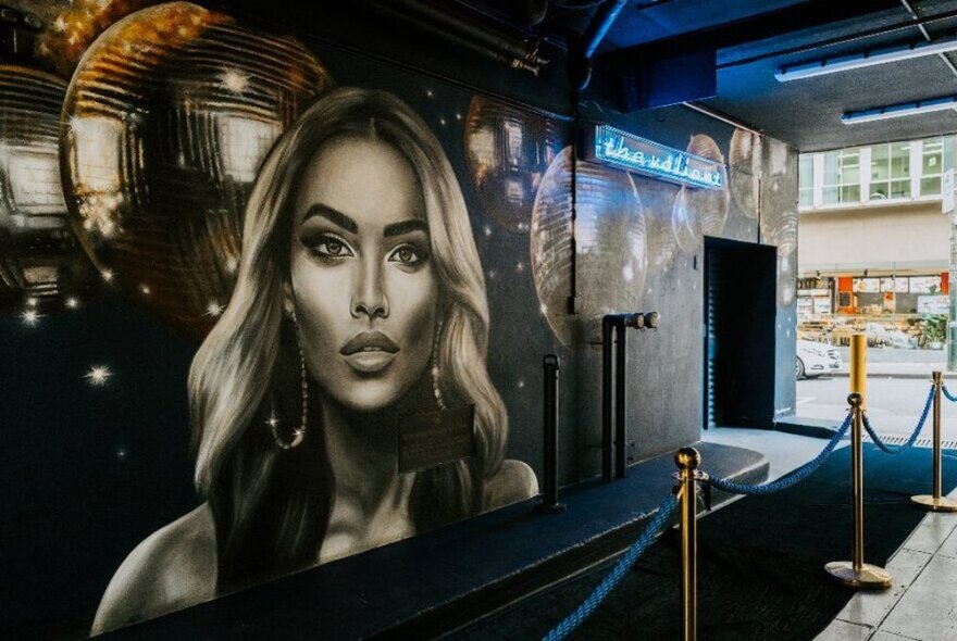 Entrance to the Valiant Cocktail Bar showing a painted mural on the outside wall, and a roped off carpeted front entrance.