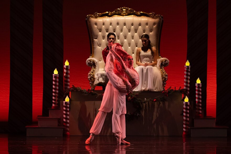 Dancers performing on stage in front of a huge throne.