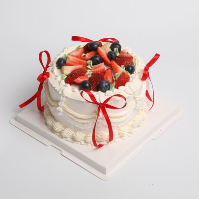 A Christmas pavlova decorated with fruit and bows.