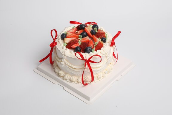 A Christmas pavlova decorated with fruit and bows.