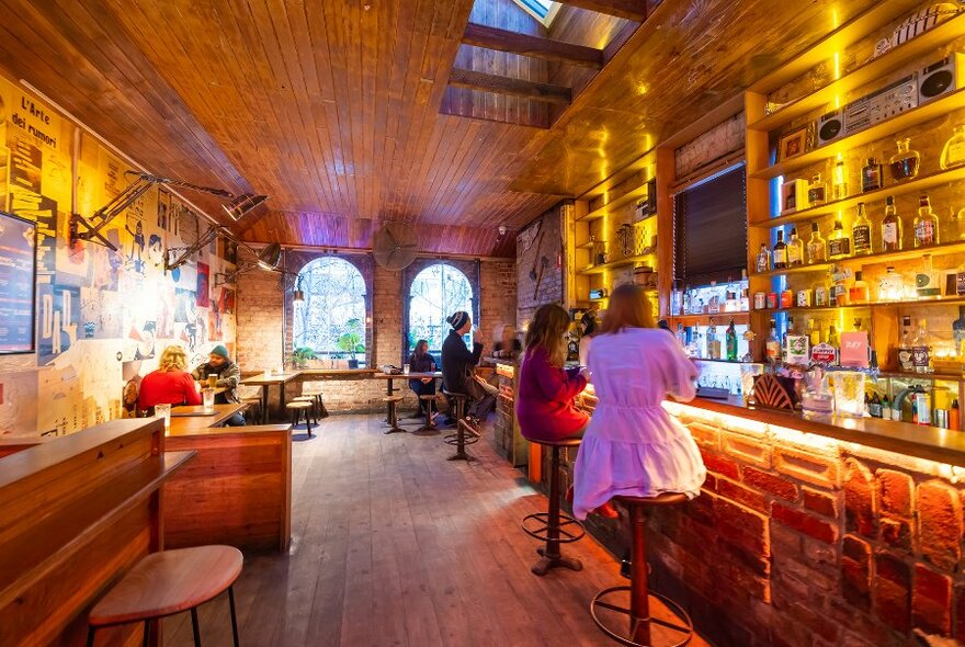 People sitting on stools at a bar with sunny windows.