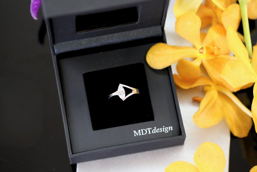 Jewellery box with ring on black velvet, with yellow flowers.