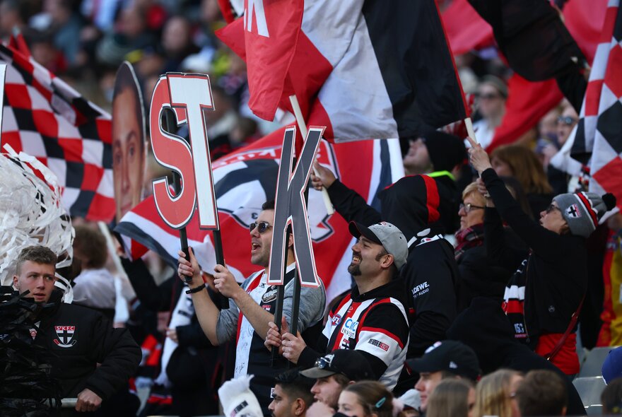 St Kilda football fans in the crowd with banners and large letters on sticks. 
