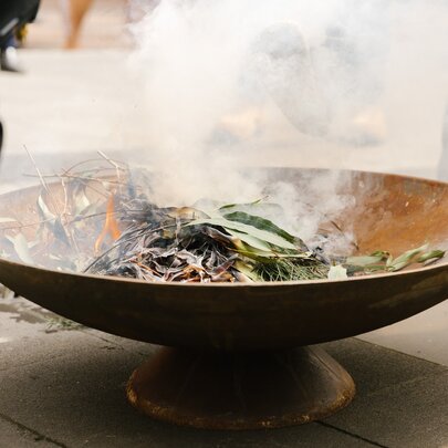 A ceramic bowl with smoking gum leaves as part of a traditional Indigenous smoking ceremony.