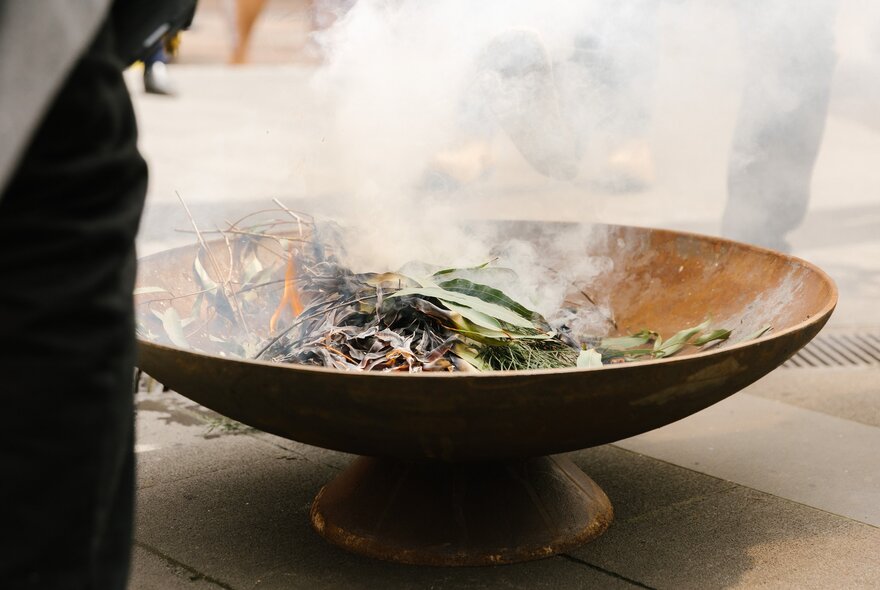 A ceramic bowl with smoking gum leaves as part of a traditional Indigenous smoking ceremony.