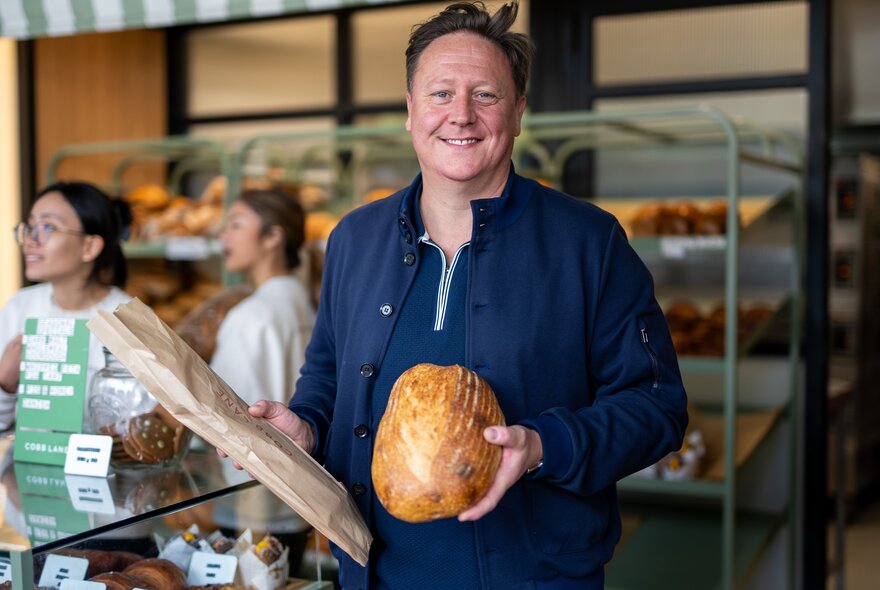 Chef Darren Purchese holding a baguette and loaf of bread.