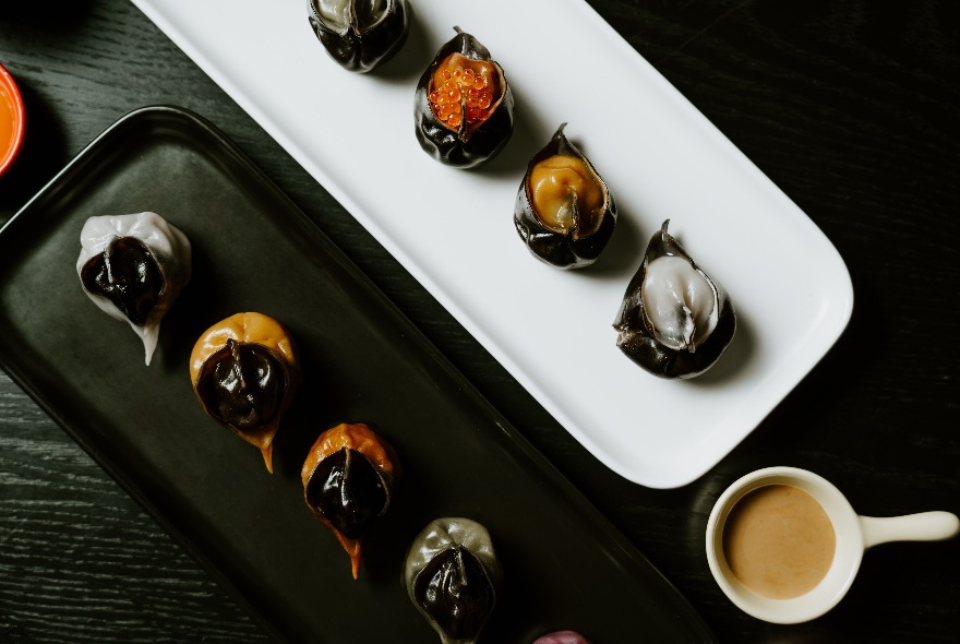 Looking down at two trays of dumplings, one white and one black. 