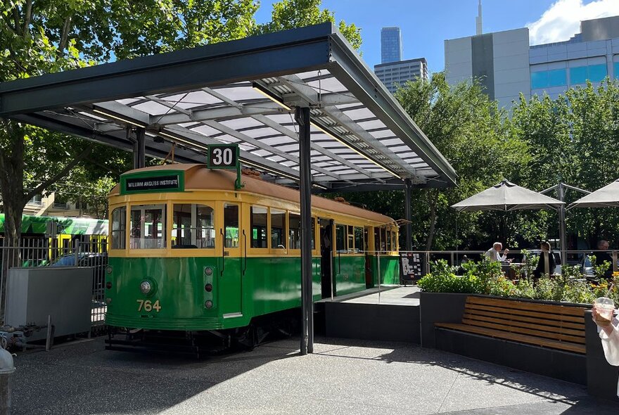 A tram parked permanently under an awning with people enjoying drinks outside.