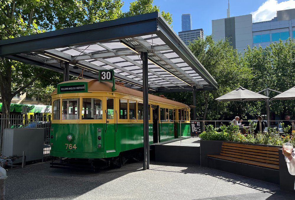 A tram parked permanently under an awning with people enjoying drinks outside.