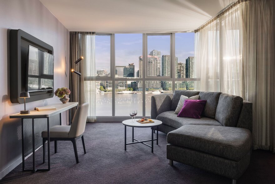 Sebel Docklands hotel apartment with a tv on the wall and a curved sofa.
