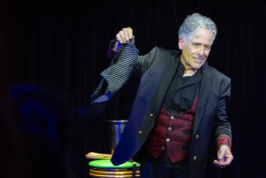 A man performing a magic show on stage, with props.